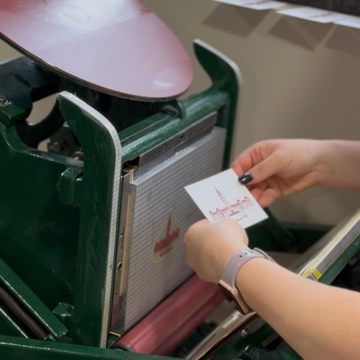 Person using a vintage letterpress machine to print a card.