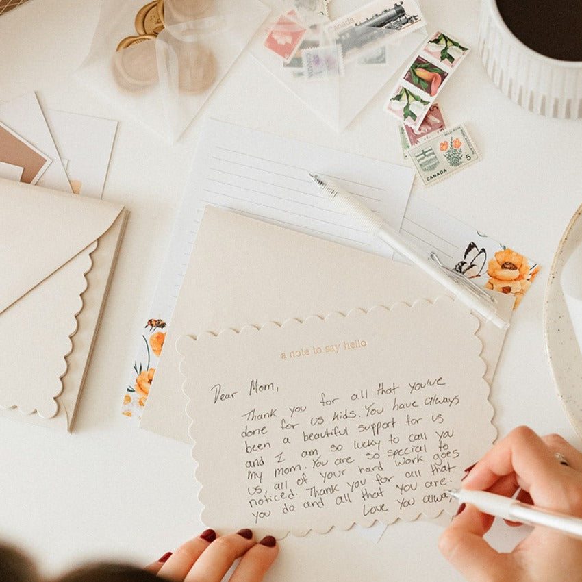 someone writing a letter using the tools in the stationery subscription box