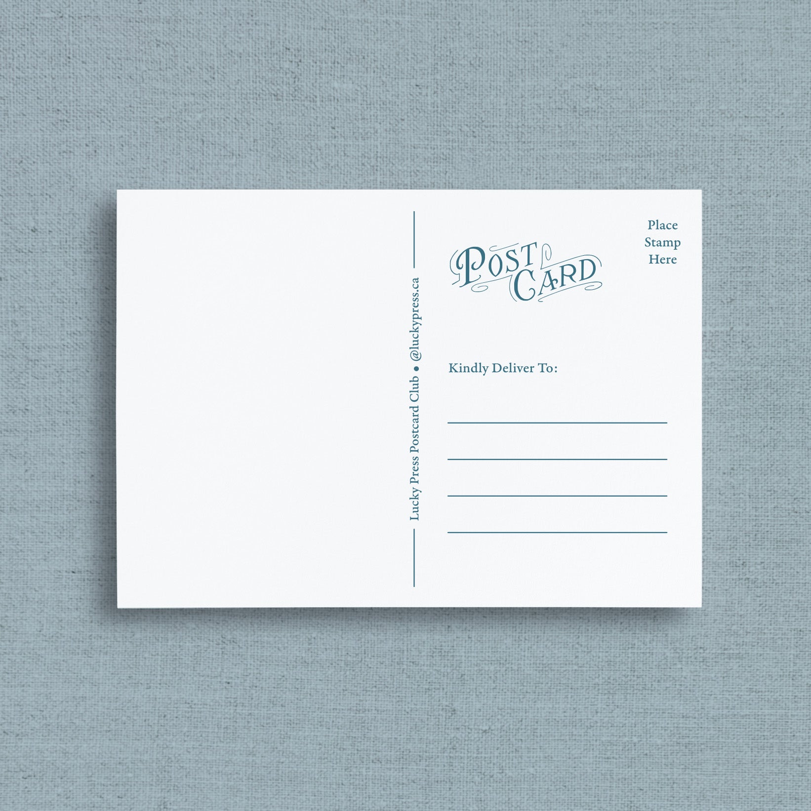 Reverse side of post card with blue printed text and lines, displayed flat against a textured light blue-gray background. The postcard features the words 'Post Card' in blue script, along with fields for destination and stamp placement.